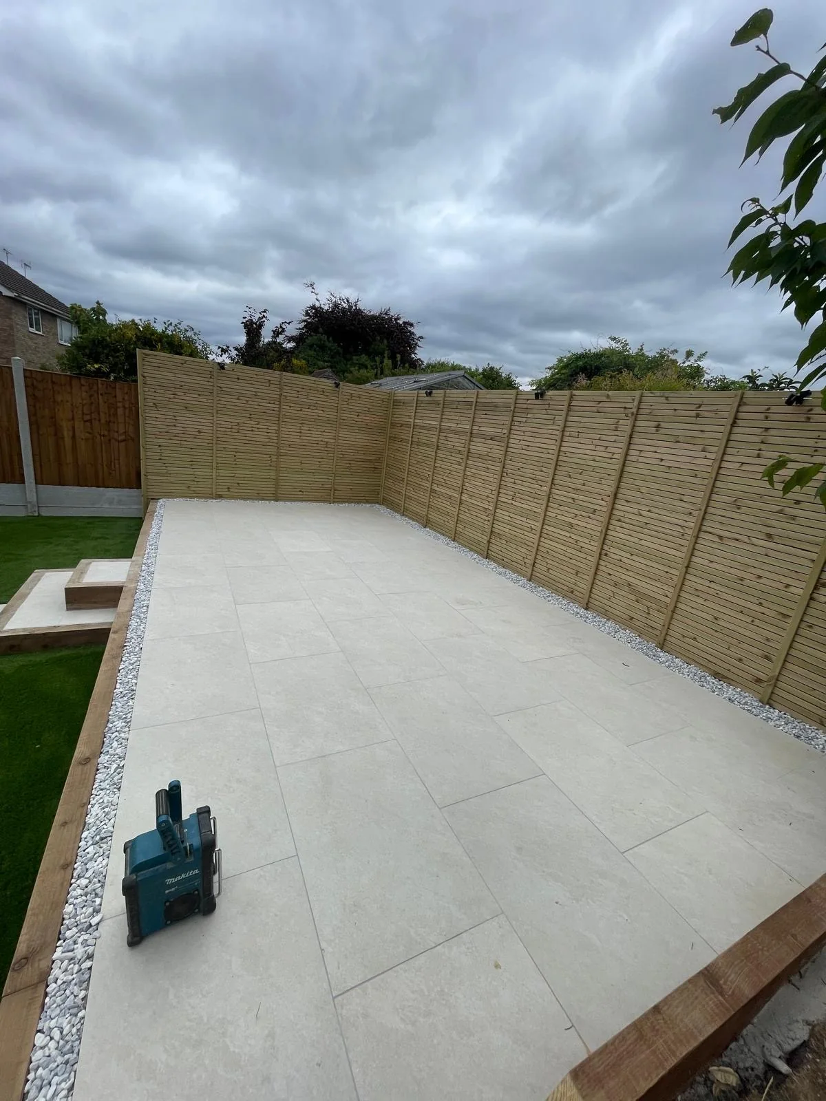 Large pale paved garden area with fencing